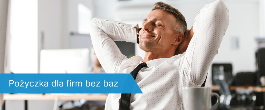 Uśmiechnięty mężczyzna w koszuli i krawacie, odchylony w fotelu z rękami za głową, rozmawia przez telefon